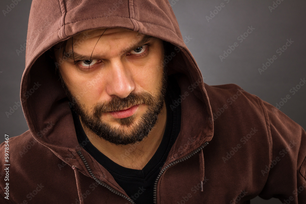 Close-up portrait of threatening man with beard wearing a hood