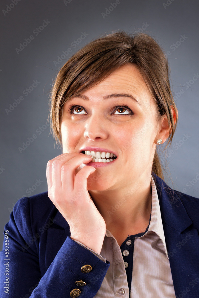Closeup portrait of a nervous young businesswoman biting her fin