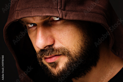 Close-up portrait of threatening  man with beard wearing a hood