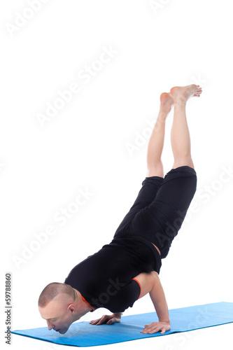 Athletic man doing yoga handstand in studio