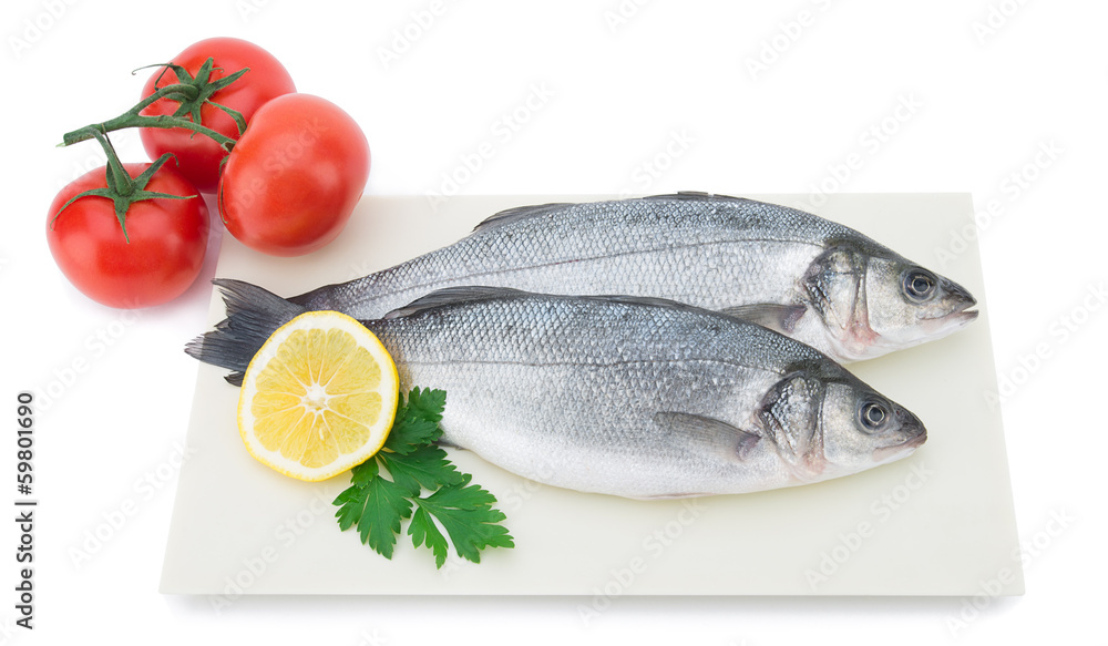 Fresh sea bass with vegetables on plate isolated on white Fresh sea bass with vegetables on plate isolated on white