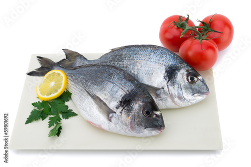 Fresh raw fish with vegetables on plate isolated on white