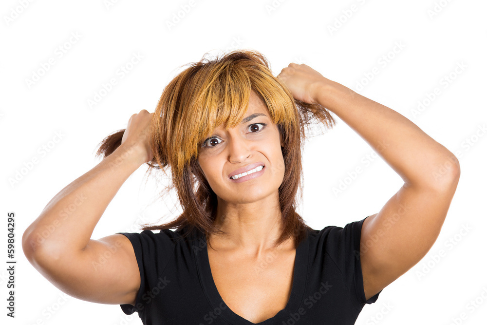 Closeup portrait young stressed woman pulling her hair out Closeup portrait young stressed woman pulling her hair out