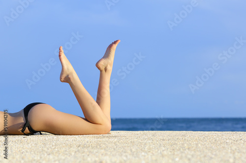 Beautiful smooth model legs resting on the sand of the beach