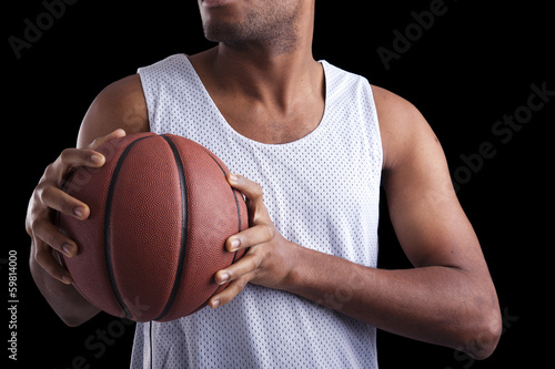Basketball player holding a ball against dark background © cristovao31