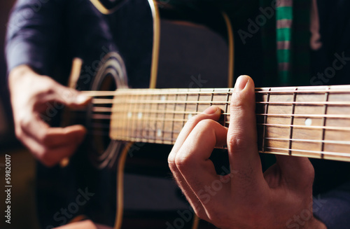 Man playing music at black wooden acoustic guitar