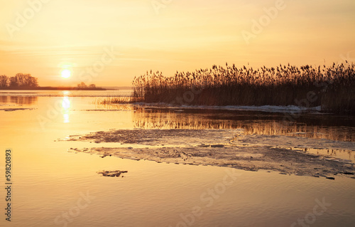 Winter landscape with river and sunset fiery sky. © es0lex