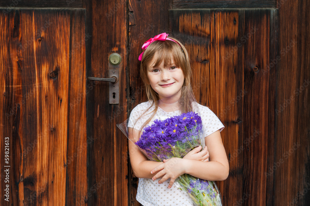 Fototapeta premium Summer portrait of a cute little girl with purple flowers