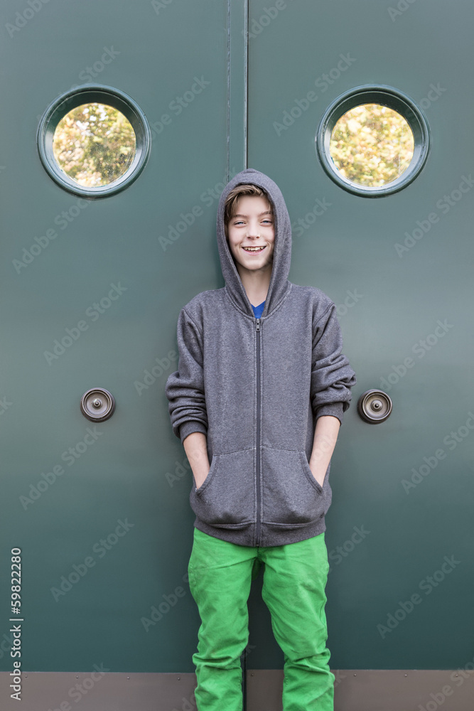 portrait of a smiling male teenager in front of a green metal do