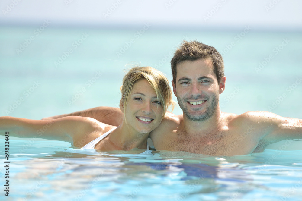 Couple swimming in infinity pool Couple swimming in infinity pool