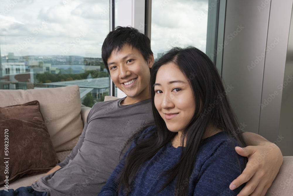 Portrait of happy loving couple sitting on sofa at home Portrait of happy loving couple sitting on sofa at home