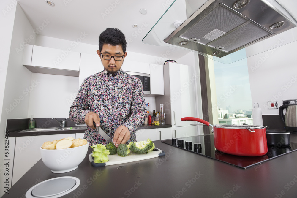 Man cutting broccoli at kitchen counter Man cutting broccoli at kitchen counter