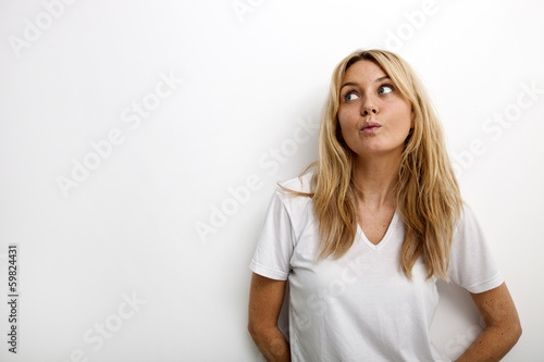 Thoughtful woman puckering against white background