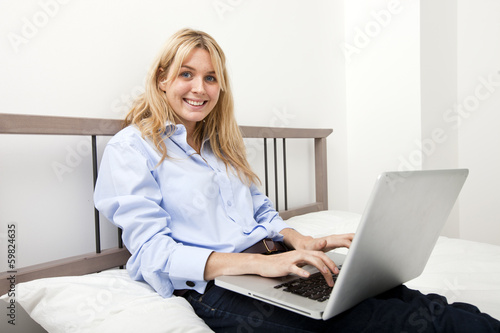 Portrait of businesswoman using laptop in bed