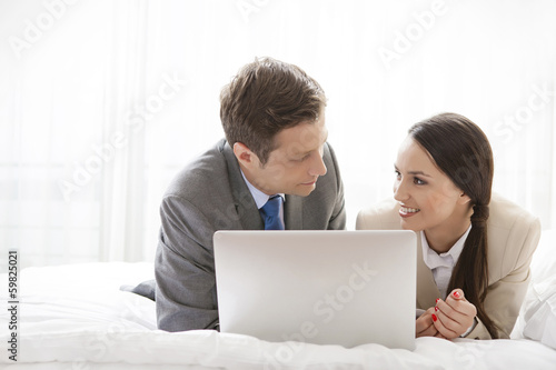 Business couple with laptop looking at each other in hotel room