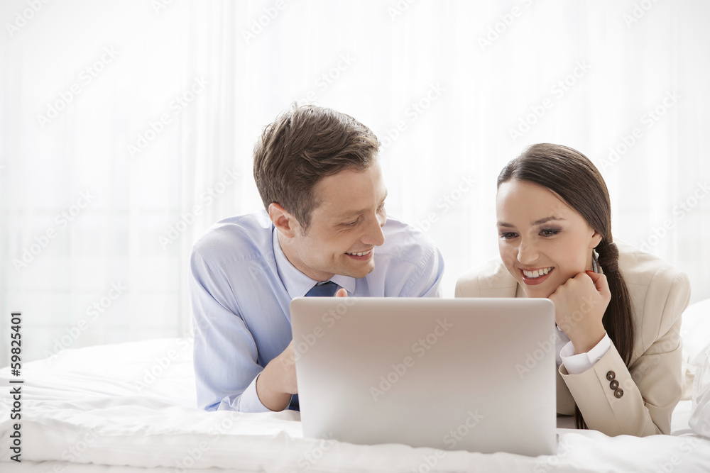 Young business couple using laptop in hotel room