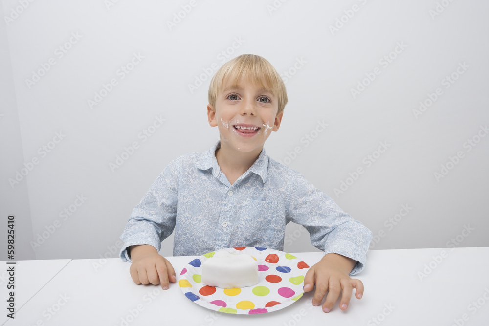 Portrait of happy boy with cake slice in plate on table at home Portrait of happy boy with cake slice in plate on table at home