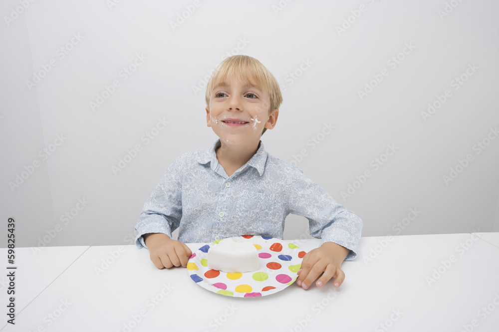 Smiling boy with cake slice in plate on table at home Smiling boy with cake slice in plate on table at home
