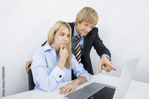 Businessman showing something to coworker on laptop in office © moodboard