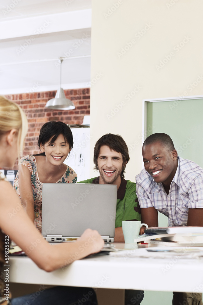Four people having meeting around laptop laughing. Four people having meeting around laptop laughing.