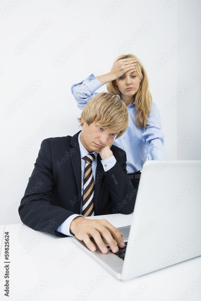 Frustrated businesspeople using laptop at desk in office Frustrated businesspeople using laptop at desk in office