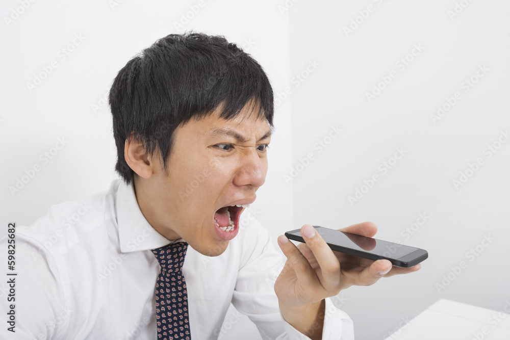 Frustrated mid adult businessman screaming on cell phone in office Frustrated mid adult businessman screaming on cell phone in office