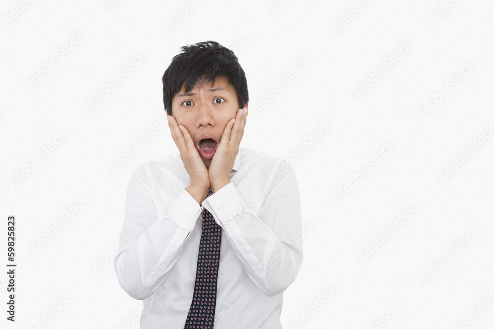 Shocked mid adult businessman with hands on face over white background Shocked mid adult businessman with hands on face over white background