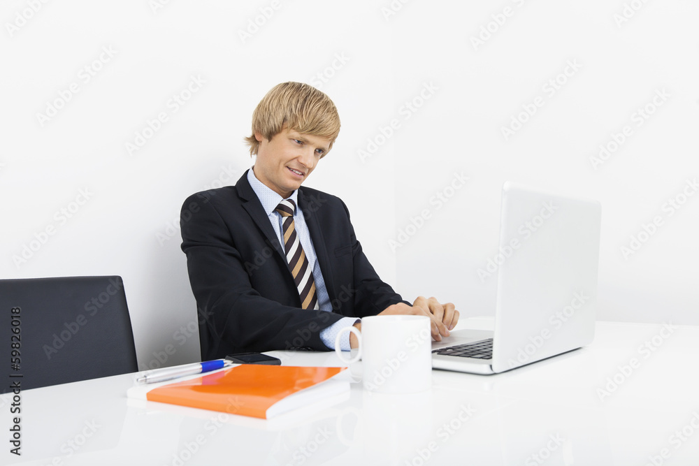 Confident businessman using laptop at desk in laptop Confident businessman using laptop at desk in laptop