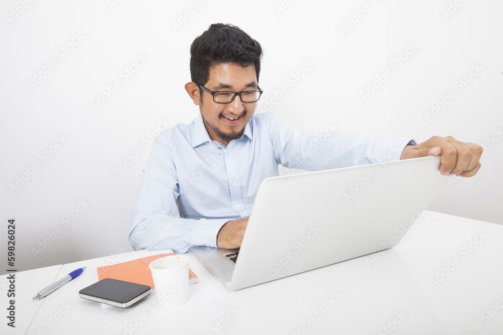 Smiling businessman working on laptop at desk in office Smiling businessman working on laptop at desk in office