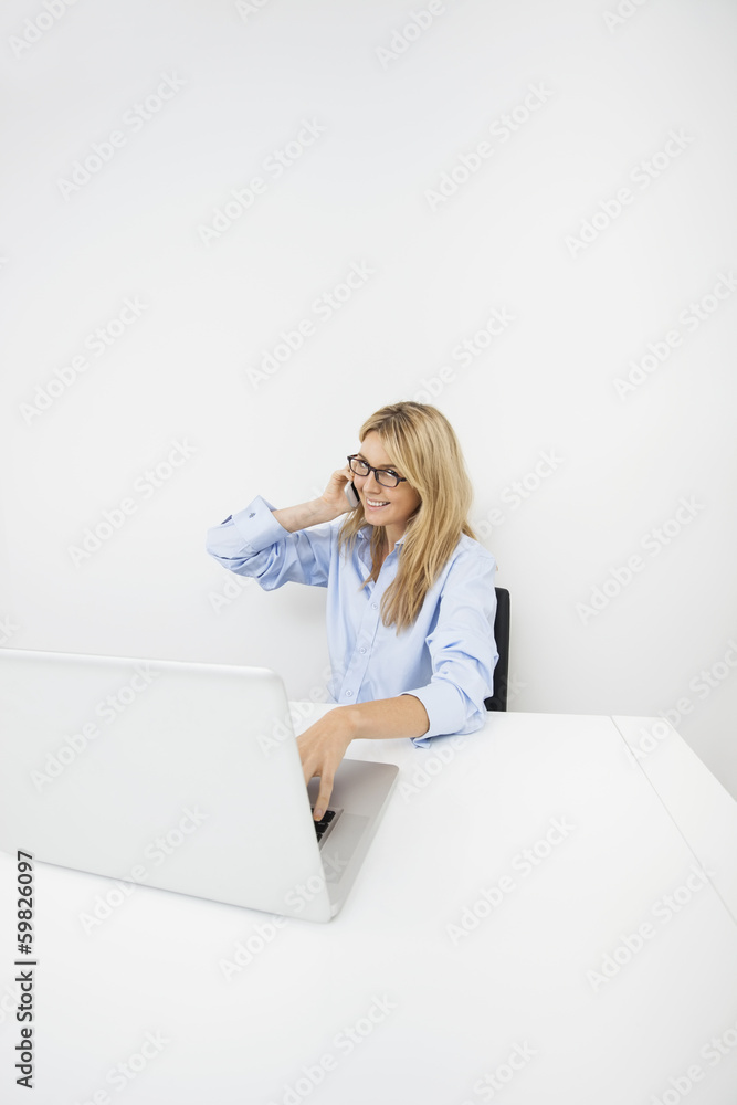 Portrait of smiling businesswoman answering smart phone in office Portrait of smiling businesswoman answering smart phone in office