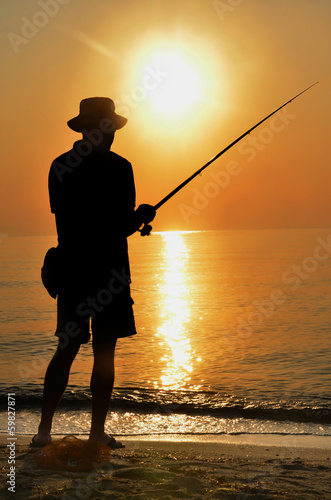 Fisherman silhouette on the beach at colorfull sunset