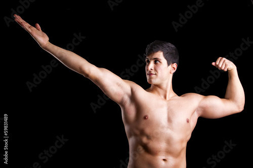 Muscle young man posing against a dark background