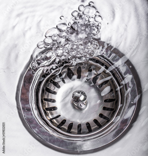 Water flowing down the hole in a kitchen sink © akulamatiau