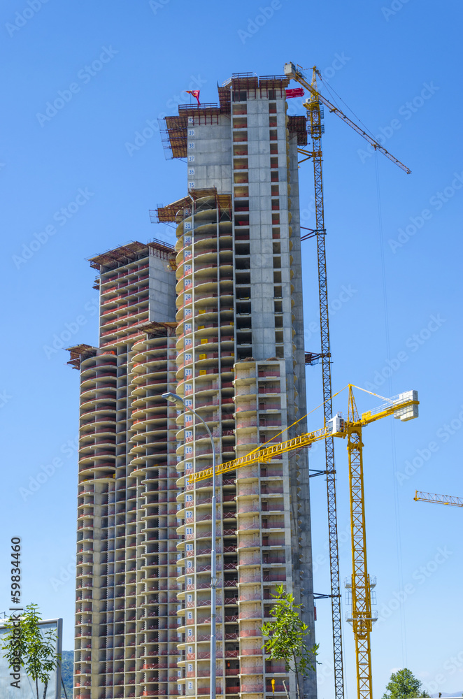 Fototapeta premium Inustrial construction cranes working on building a skyscraper