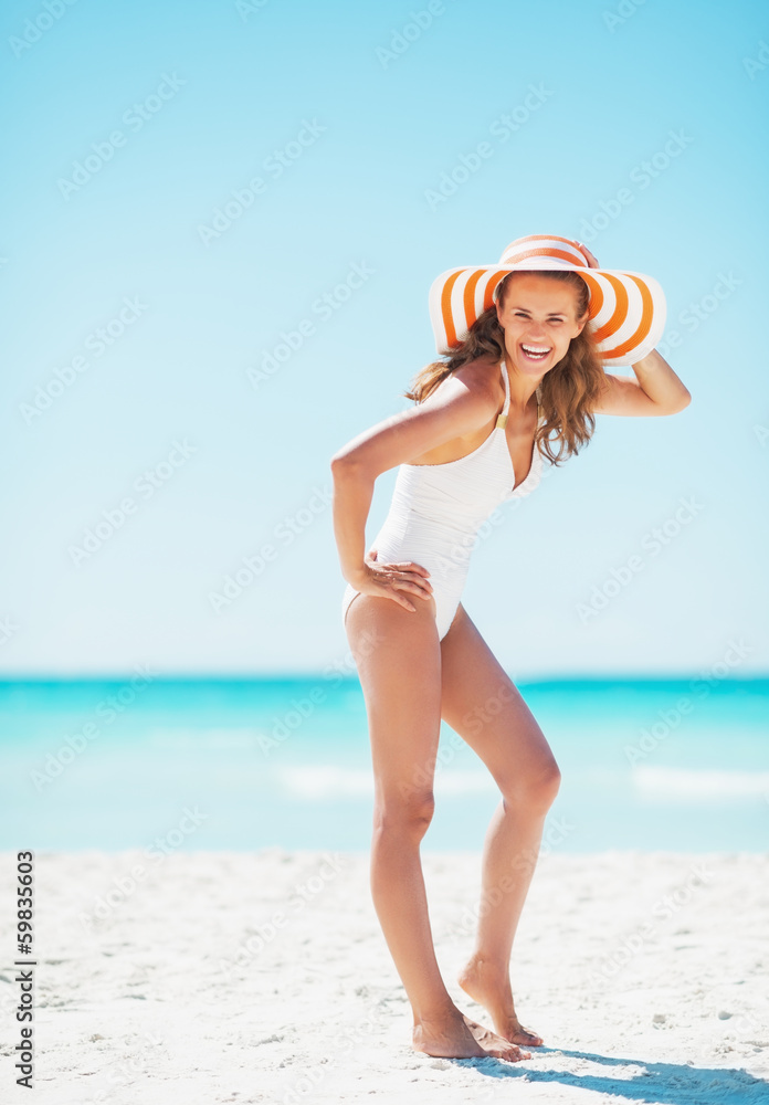 Full length portrait of young woman in hat on beach