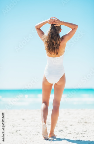 Young woman standing on beach. rear view