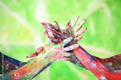 Interlacing female and male hands in paint of different colors photo