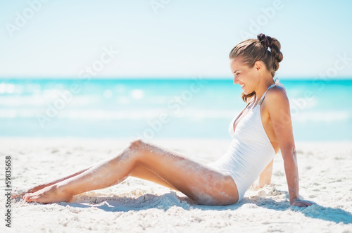 Happy young woman sitting on beach © Alliance