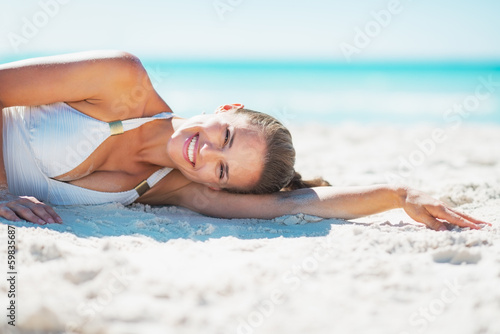 Portrait of smiling young woman laying on beach