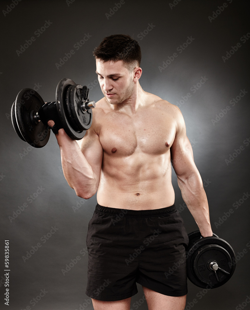 Athletic man working out with heavy dumbbells