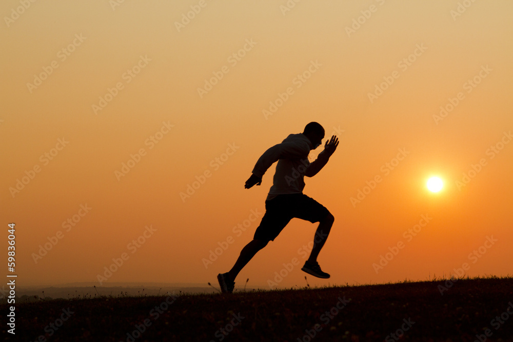 Sunset silhouette of a man running uphill Sunset silhouette of a man running uphill