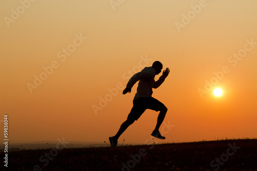 Obraz na płótnie Sunset silhouette of a man running uphill