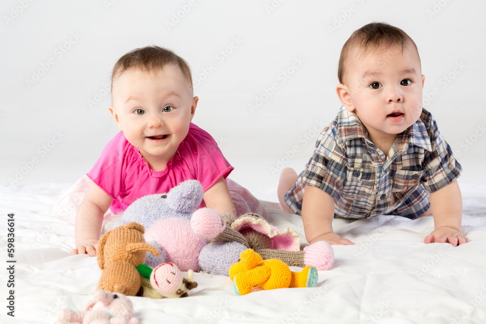 Two babies playing with knitted toys in studio Two babies playing with knitted toys in studio