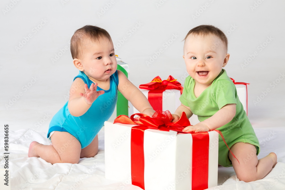 Two beautiful babies with a gift box on the floor in studio Two beautiful babies with a gift box on the floor in studio