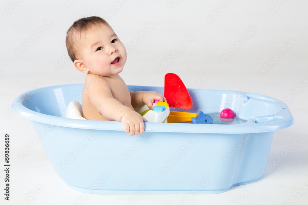 Smiling baby boy bathes in a bathtube with toys Smiling baby boy bathes in a bathtube with toys