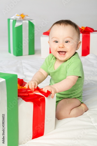 Smiling baby girl with a gift box on the floor in studio photo