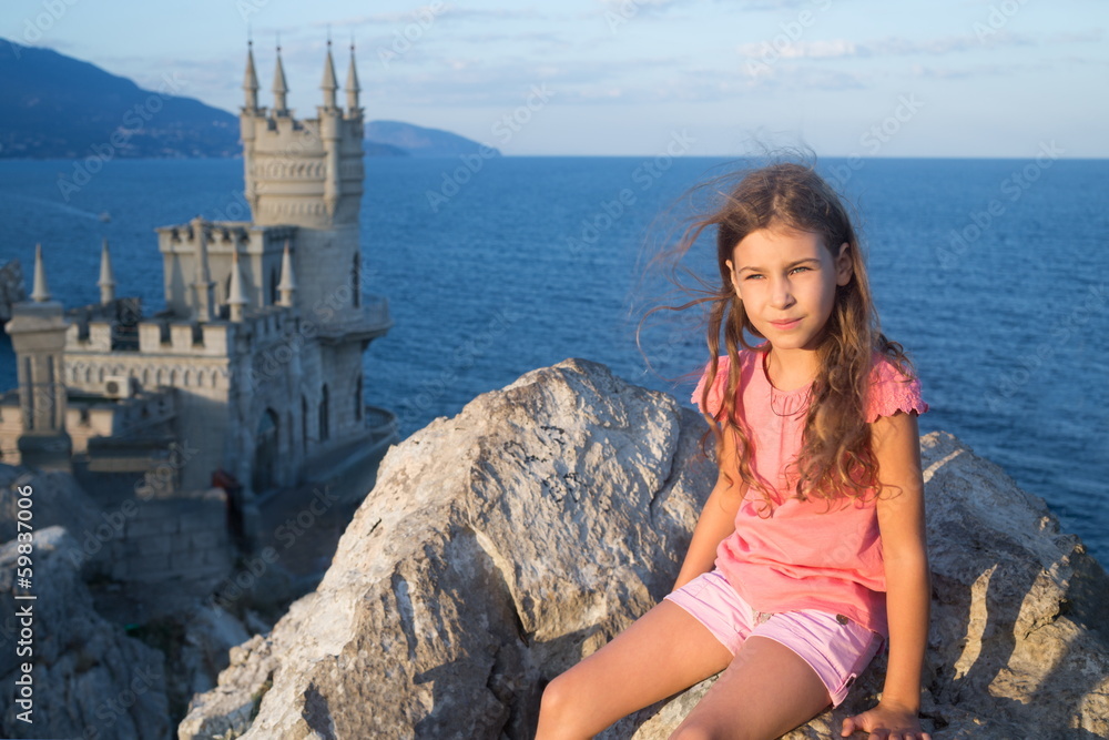 Little girl on the nature with old castle and the sea