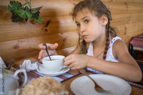 Little girl sitting in a cafe at the table with an empty plate