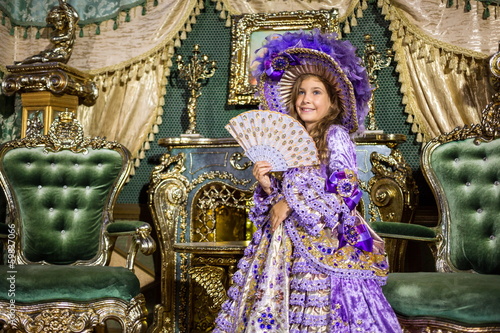 girl in old-fashione dress with fan in beautiful room