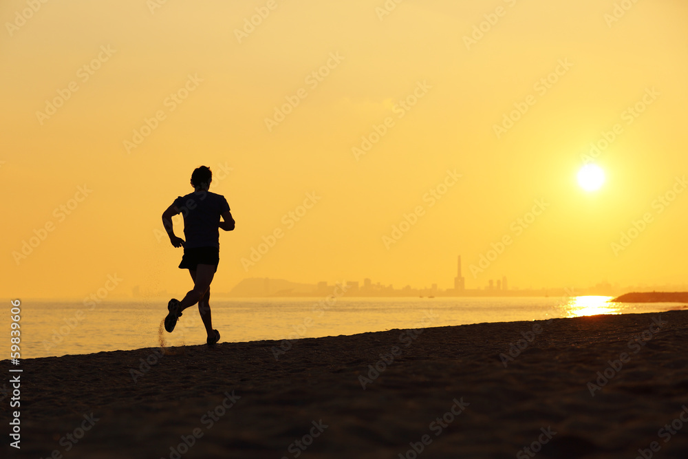 Jogger silhouette running on the beach at sunset